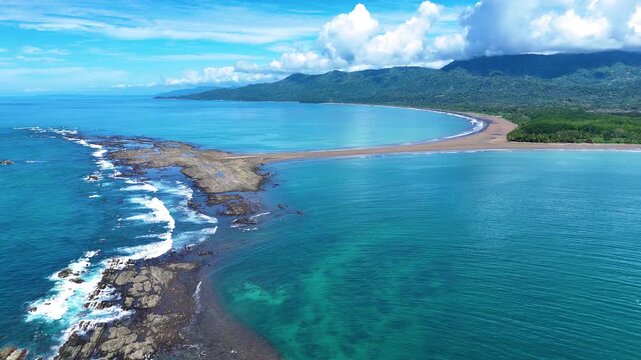 Smooth orbit drone shot around the Whale Tail sandbar in Uvita showing the tropical beach, Pacific Ocean and iconic coastal formation.