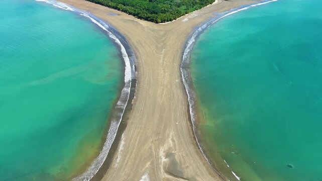 Top down drone view over the narrow section of the Whale Tail sandbar, showing ocean currents and symmetry in Uvita, Costa Rica.