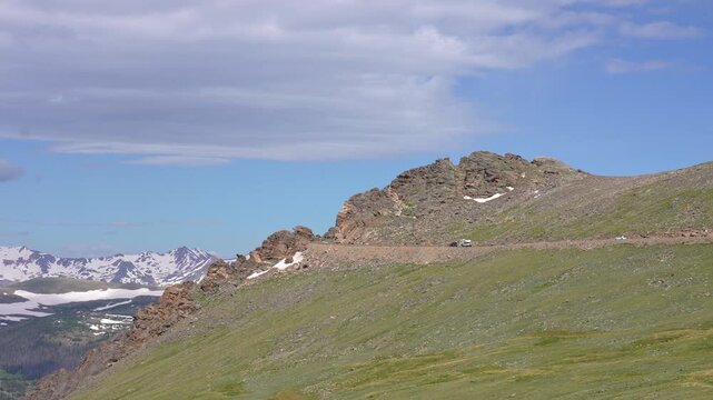 Multiple cars driving along the most scenic section of Trail Ridge Road in Rocky Mountain National Park, Colorado. Breathtaking mountain landscapes and winding alpine roads showcasing the beauty of th