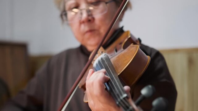 closeup elderly asian violinist practicing precise fingerwork and bow control in quiet studio -  focused hands on strings -  warm wooden instrument -  patient teaching atmosphere -  rehearsal and