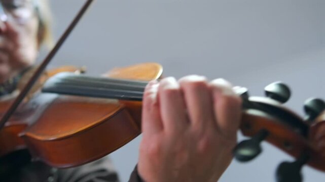 Elderly female music instructor plays the violin -  demonstrating bowing and finger technique during a private music lesson. Music teacher demonstrating violin technique during lesson