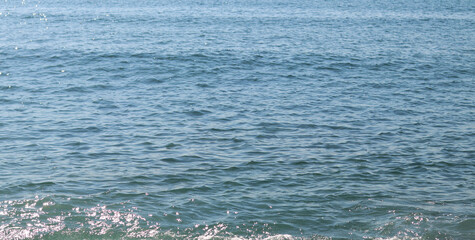 Obraz premium Sea, background. Side view of the sea surface covered with rough waves. Surface of the Black Sea. Seaside vacation, resort, summer season