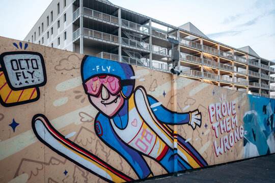 Milan, Italy - May 23, 2025: Street art murals painted on a construction site fence in the Lambrate district, with modern residential buildings under development in the background