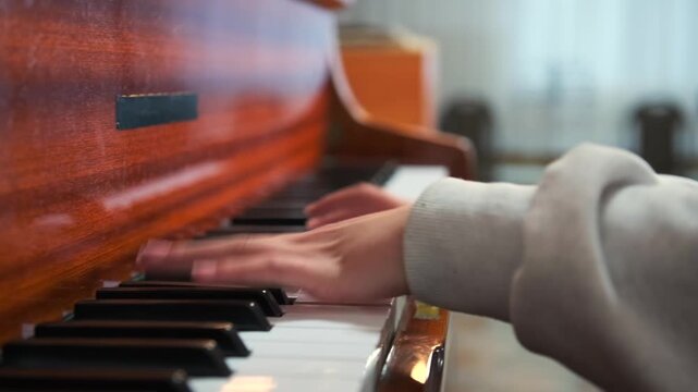 Close-up of young woman hands playing harmonium at home -  side view. Cozy music-making process. Home studio -  solo creativity -  and acoustic sound.