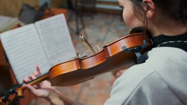 Close-up of young violin student sight-reading during an exam -  pressure of performing from sheet music in academic setting. -  with visible nervousness. Focused expression and stiff posture
