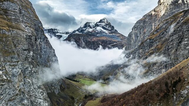 Dramatic snowy mountain peak rising above swirling valey fog aerial view