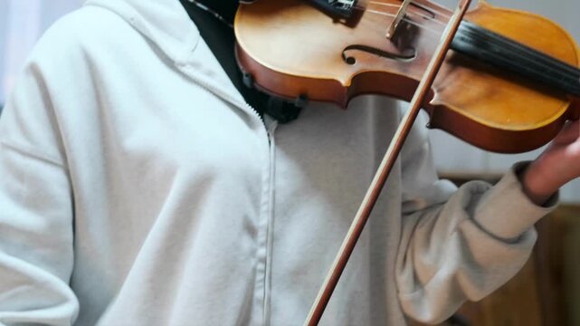 Macro view of a violin being played by a young student. Emphasis on the instrument wood grain -  and bowing technique. Music -  and craftsmanship. -  strings -  education