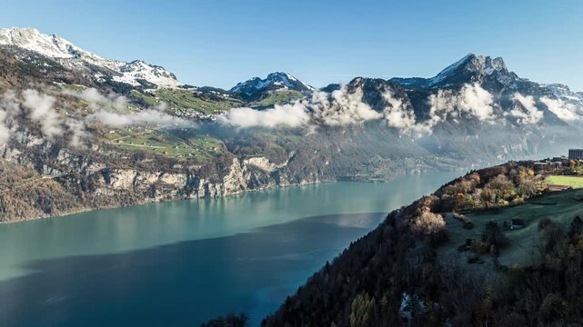 Aerial view of turquoise alpine lake with coastal roa and snowy mountains