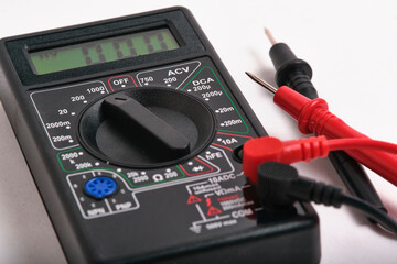 Closeup digital multimeter control panel with rotary selector switch and plugged probes. Focus on mode selection dial.