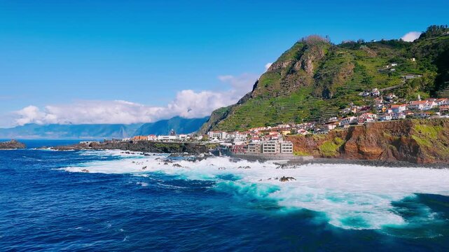 Sunlit aerial view of Porto Moniz on Madeira Island with rugged coastline and active ocean swell