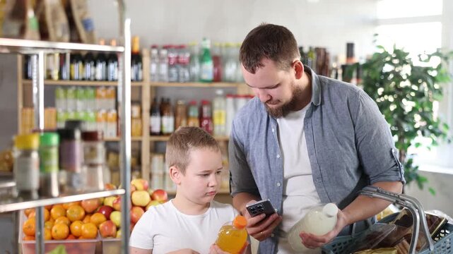 Father and son boy in store scans QR code on carbonated beverage bottle. With help of mobile app, buyers receive information about product. They checks product in registry database of national agency