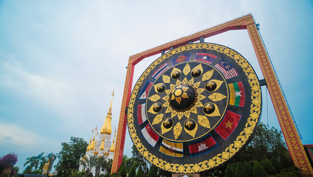 A grand, ornate ASEAN drum with vibrant flags stands majestically at a traditional Thai Buddhist temple, its intricate gold patterns, symbolizing unity, culture, and travel.