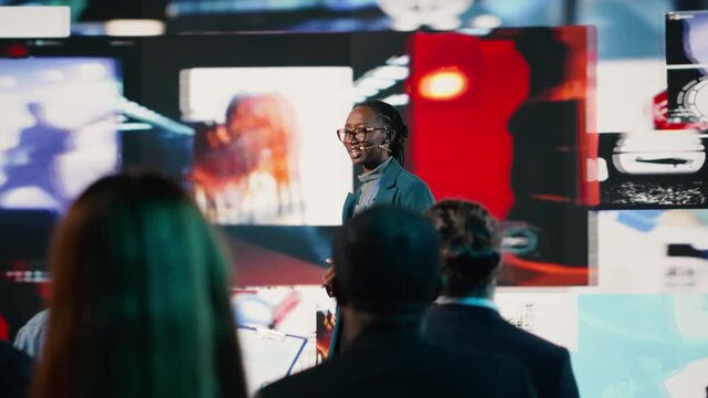 Black young adult presenter during a social media presentation at business summit. Speaker sharing digital marketing strategy, branding and communication insights at event focused on media. Camera B.