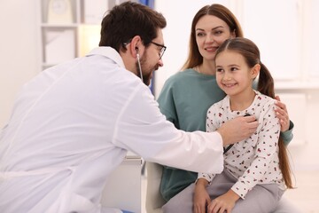 Obraz premium Little girl and her mother having appointment with pediatrician in hospital. Doctor checking child with stethoscope