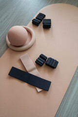 Obraz premium Minimalist flat lay of home fitness equipment including resistance bands, massage ball and hand grip strengthener on neutral beige background. Home workout, fitness and healthy lifestyle concept with 