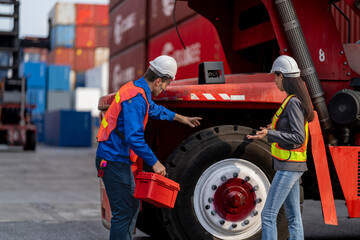Fototapeta premium Two logistics workers asian man and woman discuss operations at a busy shipping container yard. checking car folk lift machine.