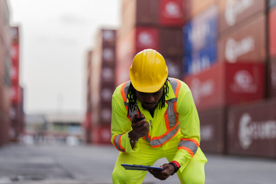 African logistics workers man cheking on site area operations at a busy shipping container yard. successful coordination in freight, transportation, and supply chain operations