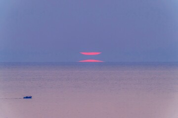 水平線の蜃気楼と幻想的な夕日 幻の太陽と静かな海の風景