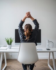 Woman stretching at her desk in a modern office space with computer