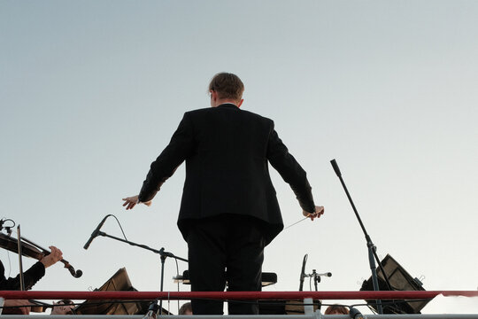 Orchestra conductor standing leading performance with baton