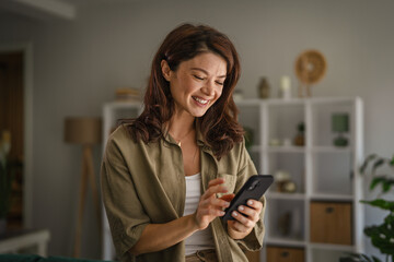 Smiling woman using smart phone at home laughing and communicating