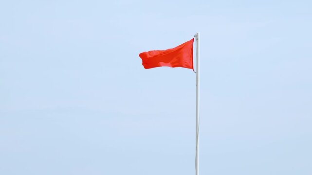 Red warning flag waving in clear sky