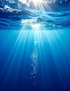 Rayos de sol atraviesan el agua azul profunda, iluminando burbujas que ascienden hacia la superficie en un paisaje submarino sereno y radiante.