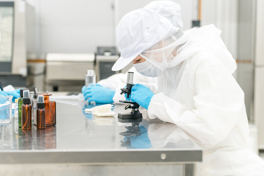薬品工場,製薬会社で薬品開発をするクリーンスーツを着たスタッフ