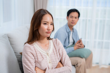 Obraz premium Angry asian couple sitting sofa with conflict and frustrated, woman ignoring boyfriend, toxic relationship problem and argument, stress and tension, feeling disappointed and sad, worried and upset.