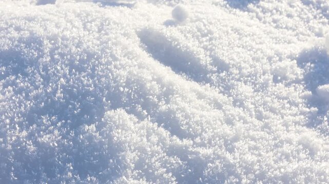 Sunlit snow outdoors, closeup. Camera moving up and right