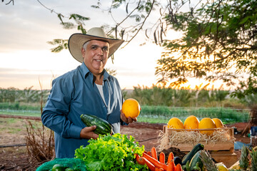 Smiling Senior Farmer Holding Fresh Organic Vegetables at Sunset on a Farm