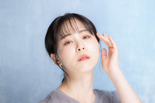 水色背景で美容やスキンケアの明るいイメージのクローズアップカメラ目線アンニュイな表情