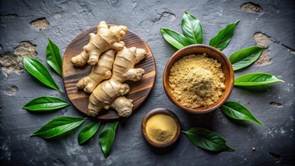 Fototapeta premium A wooden plate with fresh ginger roots and bowls of ginger powder on a dark stone surface surrounded by green leaves