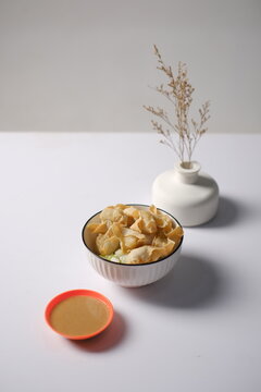 Indonesian batagor served in a bowl with crispy fried dumplings, fresh cucumber, and peanut sauce on a clean white background, ideal for street food, menu display, culinary content, and food branding.