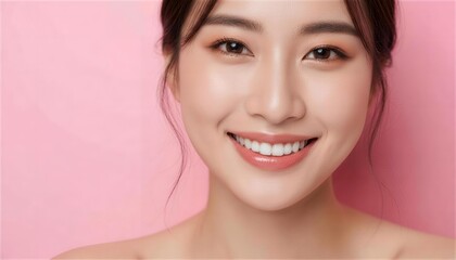 ピンクの背景で微笑む肌の綺麗な若い日本人女性