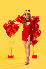 Fototapeta premium Beautiful woman dressed as Cupid with balloons on yellow background. Valentine's Day celebration