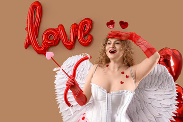 Fototapeta premium Sexy young woman dressed as Cupid with bow and balloons on beige background. Valentine's Day celebration
