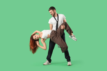 Young couple of hip-hop dancers on green background