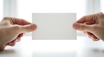 Obraz premium Minimalist mockup featuring human hand holding a blank white business card or invitation against a bright sunny backdrop for professional branding identity and corporate presentation.