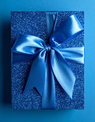 Sparkling Blue Gift Box with Satin Ribbon Bow on a Blue Background.