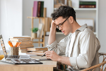 Thoughtful male screenwriter writing script at table in office