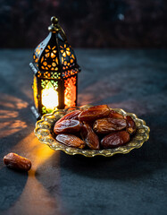 Dried dates in golden bowl with glowing Ramadan lantern