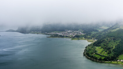 Naklejka premium Scenic view of Sete Cidades, San Miguel Island, Azores. Twin lakes surrounded by lush greenery and mountains. Misty landscape with a foggy atmosphere.