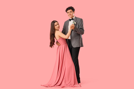 Pretty prom couple dancing valse on pink background