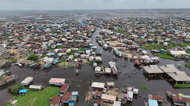 A wide aerial angle of Ganvie, the largest floating village in Africa, showcasing the dense network of stilt houses and traditional boats