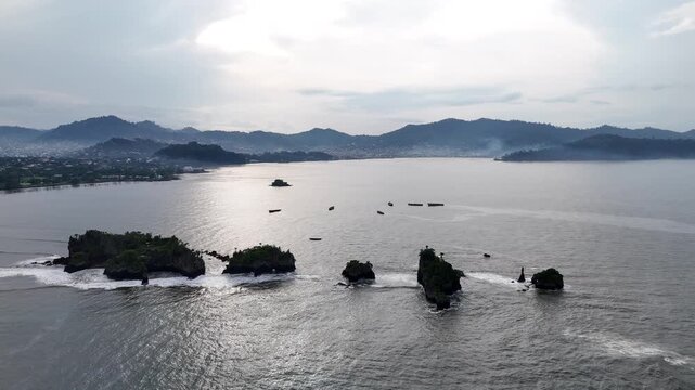 A stunning high-angle perspective of the Limbe coastline in Cameroon, featuring several dark volcanic islets scattered across the calm waters of the Atlantic Ocean under an overcast sky