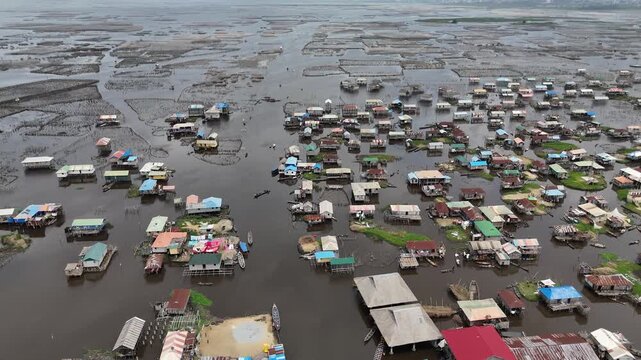 A cinematic high-angle drone perspective of Ganvie, the largest floating village in Africa, showcasing the intricate layout of wooden houses on water