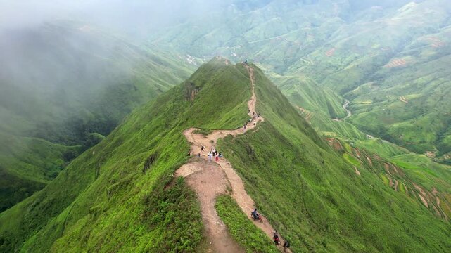 Close-up 4K drone tracking shot following the narrow mountain path on Dinosaur Backbone ridge. Steep cliffs and dramatic highland scenery in North Vietnam.