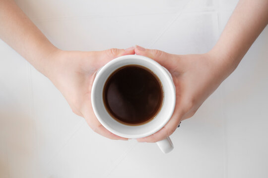 Toma cenital de Primer plano de manos, abrazando taza con caf&eacute; y fondo blanco