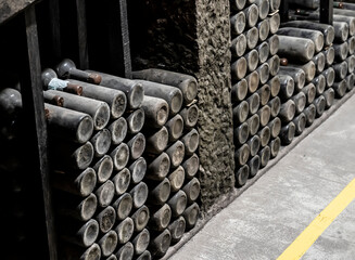 Old wine storage, Vintage wine bottles resting on dusty shelves, Antique bottles of wine stacked in shadowy cellar with faded labels